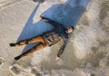 Top view of young bearded man laying flat on frozen snow looking upward. White copy space background