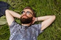 Top view of a young bearded man relaxing on the grass with his hands under the head Royalty Free Stock Photo