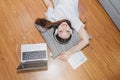 Top view of young beautiful asian woman with headphone and listening music from laptop while lying on the floor at home Royalty Free Stock Photo