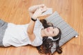 Top view of young beautiful asian woman with headphone and listening music from smartphone while lying on the floor at home Royalty Free Stock Photo