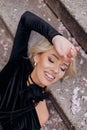 Top view of young beautiful with closed eyes woman lying on concrete stairs, putting hand on forehead among pink petals. Royalty Free Stock Photo