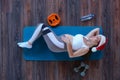 Top view of young beautiful pregnant girl in Santa Claus hat lying on the mat on the floor in a gym near to dumbbells, a Royalty Free Stock Photo