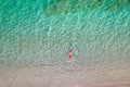 Top view. Young beautiful woman in a red hat and bikini lying and sunbathe in sea water on the sand beach. Drone, copter photo. Royalty Free Stock Photo