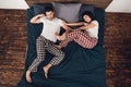 Top view. Young beautiful woman in pajama pushes adult sleeping man from bed.