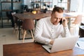 Top view of young business man wearing casual clothing working on laptop and talking on phone Royalty Free Stock Photo