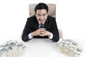 Top view of young businessman and two big piles of money on desk