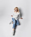 Top view of young cheerful blond woman in casual clothing, white sneakers and sunglasses sitting on floor and smiling Royalty Free Stock Photo