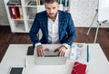 Top view of young contemporary manager or employee making notes in notebook while browsing in the net and analyzing online data Royalty Free Stock Photo