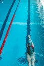 Top view of a young female swimmer training in the pool, swimming on her back underwater. Floats under water and blows Royalty Free Stock Photo