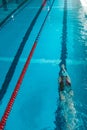 Top view of a young female swimmer training in the pool, swimming on her back underwater. Floats under water and blows Royalty Free Stock Photo