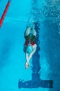 Top view of a young female swimmer training in the pool, swimming on her back underwater. Floats under water and blows Royalty Free Stock Photo