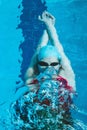 Top view of a young female swimmer training in the pool, swimming on her back underwater. Floats under water and blows Royalty Free Stock Photo