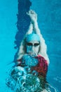 Top view of a young female swimmer training in the pool, swimming on her back underwater. Floats under water and blows Royalty Free Stock Photo