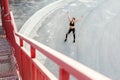 Top view of young happy beautiful sporty girl in black sportwear standing with raised arms and celebrate reaching goal of training