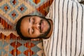 Top view of indian man laying on carpet at home with closed eyes Royalty Free Stock Photo