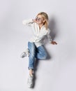 Top view of young joyful blond woman in casual clothing, white sneakers and sunglasses sitting on floor and smiling Royalty Free Stock Photo