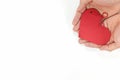 Top view of young male cupped hands holding a red heart shape tag in white background. Non-materialistic love is the best gift.