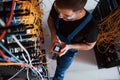 Top view of young man in uniform with measuring device that works with internet equipment and wires in server room Royalty Free Stock Photo