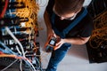 Top view of young man in uniform with measuring device that works with internet equipment and wires in server room Royalty Free Stock Photo