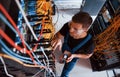Top view of young man in uniform with measuring device that works with internet equipment and wires in server room Royalty Free Stock Photo