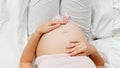 Top view of young pregnant woman resting in bed gently stroking and touching her belly. Beautiful pregnancy and