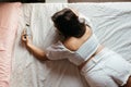 Top view of young sad woman lying on the bed looking smartphone feels unhappy. Waiting for mobile message. Feeling worried, hurt, Royalty Free Stock Photo