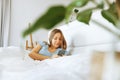 Top view young woman awaken in white cozy bed using smartphone gadget, millennial female wake up lying in bed against Royalty Free Stock Photo