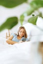 Top view young woman awaken in white cozy bed using smartphone gadget, millennial female wake up lying in bed against Royalty Free Stock Photo