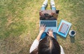 Top view of young woman in casual outfit using laptop while sitting on grass with digital tablet, notebook and smartphone. Concept Royalty Free Stock Photo