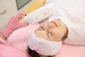 Top view of young woman lying with closed eyes, getting rejuvenation, skin-firming, deep cleaning treatment by laser.