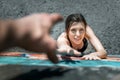 Top view of young woman raising her hands up over a street. Woman reaches up to male helping hand.