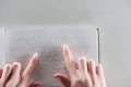 Top view of young woman reading braille text on white paper isolated on grey.