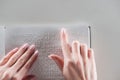 Top view of young woman reading braille text on white paper isolated on grey.