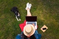 Top view of young woman sitting on grass with her dog and using laptop Royalty Free Stock Photo