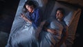 Top View: Young Woman Uses Smartphone in Bed at Night When Her Male Partner Trying to Fall Asleep