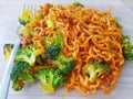 Top view. Yummy. Spicy korean instant noodles with green vegetable, broccoli on plate with fork on wood table with natural light