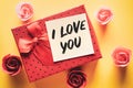 Top viewgift box with a note with the words I love you on a yellow background with buds of artificial roses Royalty Free Stock Photo