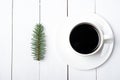 Top viewof winter composition of cup of coffee and fir tree branch on white wood background. Christmas morning in Scandinavian