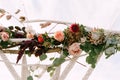 Top of the wedding arch decorated with macrame, roses, celosias and green leaves
