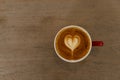 Top of white heart shape hot cappuccino coffee drink in red ceramic cup on wood table background Royalty Free Stock Photo