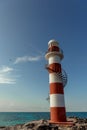 Top of a white-red lighthouse against a blue sky with an airplane. Royalty Free Stock Photo