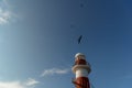 Top of a white-red lighthouse against a blue sky with an airplane. Royalty Free Stock Photo