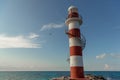 Top of a white-red lighthouse against a blue sky with an airplane. Royalty Free Stock Photo