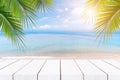 Top of wood table with seascape and palm leaves, blur bokeh light of calm sea and sky at tropical beach background.blurred blue Royalty Free Stock Photo