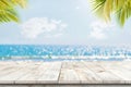 Top of wood table with seascape and palm leaves, blur bokeh light of calm sea and sky at tropical beach background Royalty Free Stock Photo