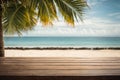 Top of wood table with seascape and palm leaves, blur bokeh light of calm sea and sky at tropical beach background. Empty ready fo Royalty Free Stock Photo