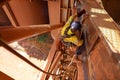 Tope view abseiler rope access repairer hanging in fall restraint position performing oxy acetylene cutting metal beam