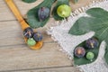 Tope view of ripe figs scattered around a wooden table with leaves and a wooden spoon