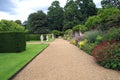 Topiary garden path with ornaments, bench, and herbaceous border Royalty Free Stock Photo