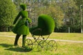 Topiary sculpture of mother with for a baby made of artificial grass. Figure of female walking with her newborn child